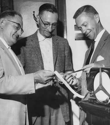 Robert Ramsey with colleagues reviewing ticket tape, ca. 1960